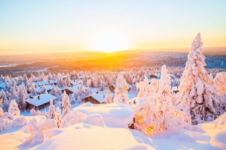 Téléchargez les photos : Superbe vue coucher de soleil sur des cabanes en bois et des arbres enneigés en Laponie finlandaise - en image libre de droit