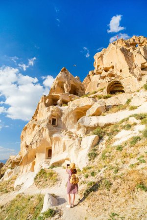 Foto de Back view of young woman exploring valley with rock formations and fairy chimneys near Uchisar castle in Cappadocia Turkey - Imagen libre de derechos