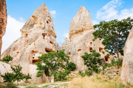 Photo for Back view of young woman exploring valley with rock formations and fairy chimneys near Uchisar castle in Cappadocia Turkey - Royalty Free Image