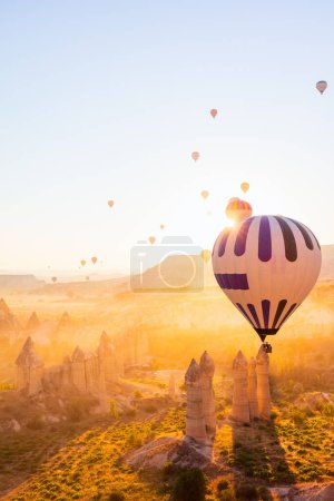 Photo for Gorgeous sunrise scenery of hot air balloons flying over Love valley with rock formations and fairy chimneys in Cappadocia Turkey - Royalty Free Image