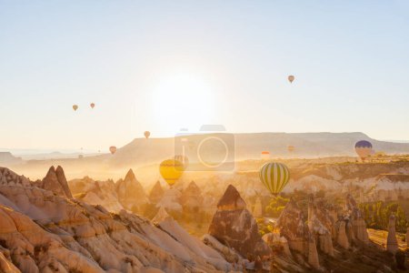 Foto de Gorgeous sunrise scenery of hot air balloons flying over Love valley with rock formations and fairy chimneys in Cappadocia Turkey - Imagen libre de derechos