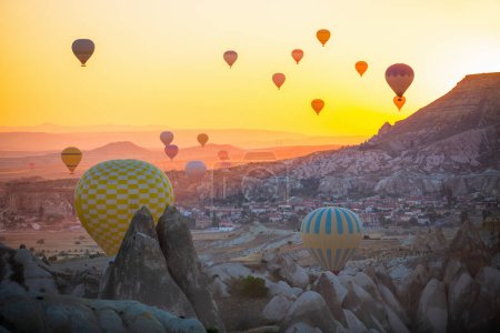 Téléchargez les photos : Gorgeous sunrise scenery of hot air balloons flying over Love valley with rock formations and fairy chimneys in Cappadocia Turkey - en image libre de droit