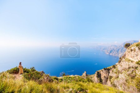 Young woman enjoying stunning view over Amalfi coast in Italy while hiking picturesque Path of the Gods trail