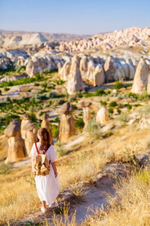 Photo for Young woman enjoying stunning sunset while hiking around beautiful valley near Cavusin village in Cappadocia Turkey with amazing rock formations and fairy chimneys - Royalty Free Image