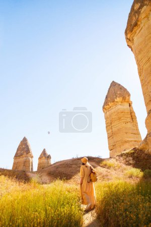 Foto de Mujer joven caminando en el valle de Gorkundere en Capadocia Turquía entre formaciones rocosas y chimeneas de hadas - Imagen libre de derechos