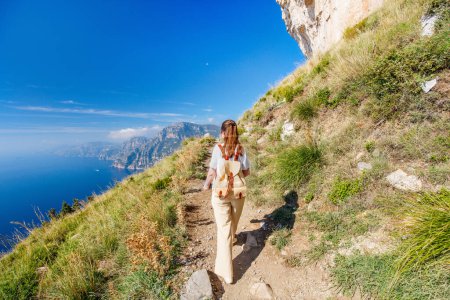 Young woman enjoying stunning view over Amalfi coast in Italy while hiking picturesque Path of the Gods trail