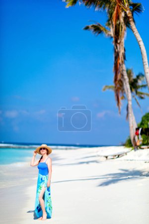 Foto de Mujer joven en la playa tropical de arena blanca rodeada de aguas turquesas del océano de Maldivas - Imagen libre de derechos