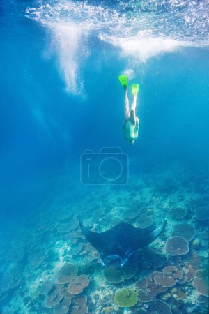 Foto de Foto submarina de una joven haciendo snorkel en un agua tropical clara con manta ray en Maldivas - Imagen libre de derechos
