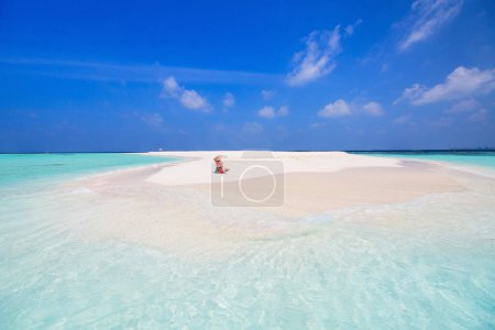 Photo for Young woman on white sand tropical beach surrounded by turquoise ocean water of Maldives - Royalty Free Image