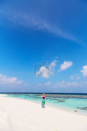 Photo for Young woman on white sand tropical beach surrounded by turquoise ocean water of Maldives - Royalty Free Image