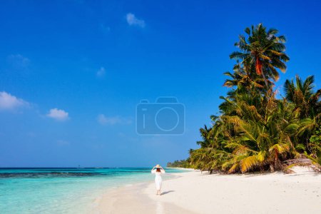 Téléchargez les photos : Jeune femme sur une plage tropicale de sable blanc entourée d'eau de mer turquoise des Maldives - en image libre de droit