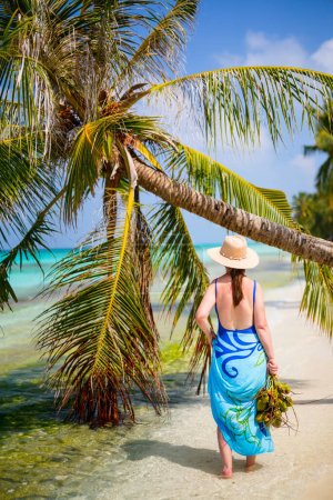 Photo for Young woman on white sand tropical beach surrounded by palm trees in Maldives - Royalty Free Image