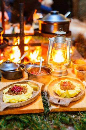 Téléchargez les photos : Nourriture traditionnelle finlandaise sautée de rennes avec purée de pommes de terre et airelles servies dans une cabane à côté d'un feu ouvert - en image libre de droit
