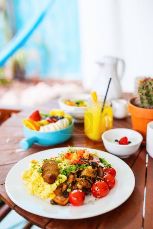 Photo for Vegetarian breakfast with scrambled eggs, roasted potatoes, plant-based sausage, sauteed mushrooms and cherry tomatoes - Royalty Free Image