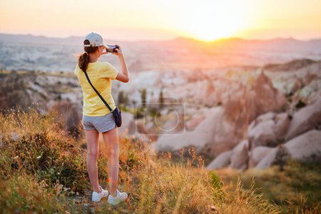 Foto de Teenage girl enjoying stunning sunset while hiking in Red valley in Cappadocia Turkey among beautiful rock formations - Imagen libre de derechos