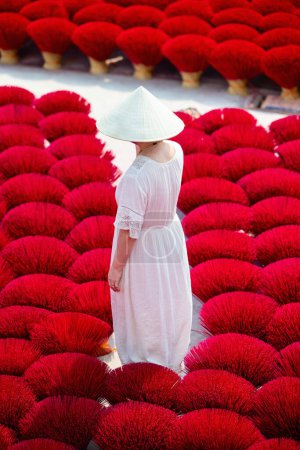 Photo for Top view of tourist woman wearing conical hat among pink incense sticks drying outdoor in village near Hanoi in Vietnam - Royalty Free Image