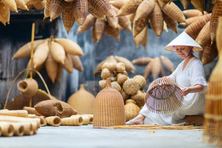 Foto de Hermosa mujer en vestido blanco y sombrero vietnamita cónico en la aldea artesanal trampa de bambú en Vietnam - Imagen libre de derechos