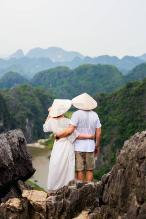 Photo for Beautiful couple enjoys travel through Southeast Asia contemplating the views of karst mountains and river of Mua Cave in Vietnam - Royalty Free Image