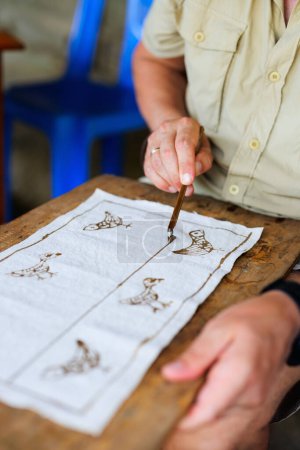 Photo for Caucasian man creating batik by drawing with hot wax - Royalty Free Image