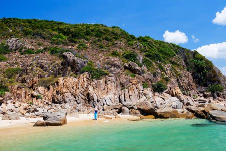 Photo for Young woman on white sand tropical beach surrounded by turquoise ocean and rocky hill in Vietnam - Royalty Free Image