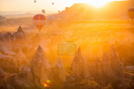 Foto de Gorgeous sunrise scenery of hot air balloons flying over Love valley with rock formations and fairy chimneys in Cappadocia Turkey - Imagen libre de derechos