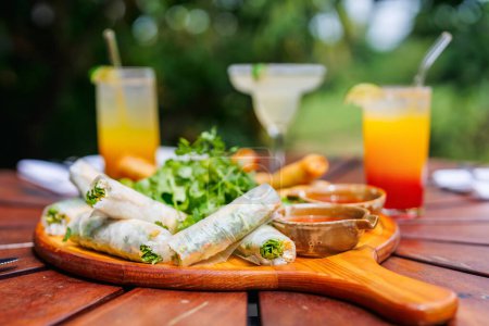 Photo for Traditional vietnamese rolls served with other small bites with tropical cocktails - Royalty Free Image