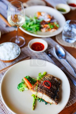 Photo for Close up of delicious grilled fish served for lunch with vegetables and white wine - Royalty Free Image