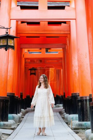 Téléchargez les photos : Belle femme marchant à travers les portes rouges Torii dans le sanctuaire Fushimi Inari à Kyoto Japon - en image libre de droit
