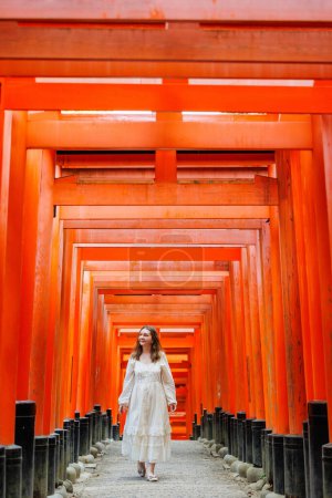 Photo for Beautiful woman walking through Red Torii gates in Fushimi Inari shrine in Kyoto Japan - Royalty Free Image