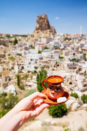 Turkish coffee in a clay cup with fortress in the city of Ortahisar on background
