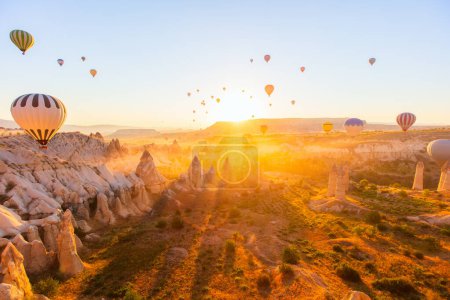 Photo for Gorgeous sunrise scenery of hot air balloons flying over Love valley with rock formations and fairy chimneys in Cappadocia Turkey - Royalty Free Image