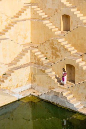Woman walking down stairs at ancient stepwell in Jaipur India