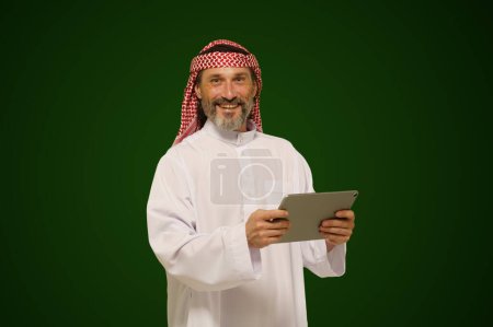 Arabischer Muslim hält ein digitales Tablet in der Hand. Konzept der Online-Kommunikation und globalen Vernetzung durch Technologie. Hochwertiges Foto