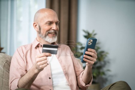 Senior Mann hält Kreditkarte in der einen Hand und Handy in der anderen. Bequemlichkeit und Zugänglichkeit digitaler Transaktionen für ältere Menschen, wobei ihre Fähigkeit zur Anpassung an moderne Technologien hervorgehoben wird. . Hoch