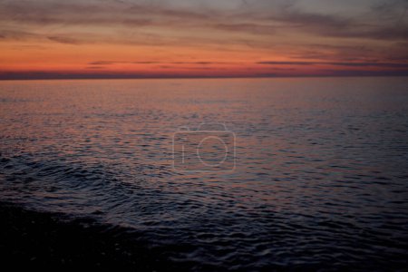Téléchargez les photos : Red sunrise over calm blue sea. Background shot in low key with copy space - en image libre de droit