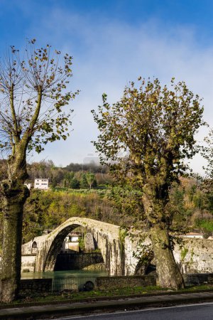Foto de El puente de María Magdalena es una estructura medieval que cruza el río Serchio. El agua fría verde del río refleja los antiguos arcos asimétricos. Italia, provincia de Toscana - Imagen libre de derechos