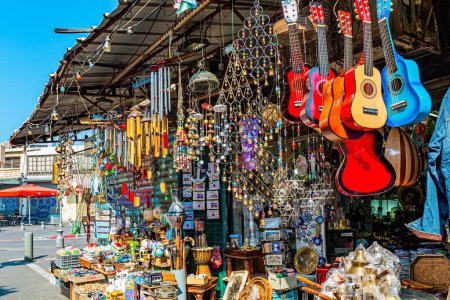 Photo for Flea market. Bright multi-colored souvenir guitars. Finjans and coffee pots. Garden decorations with jingle bells. Tel Aviv, Israel. - Royalty Free Image