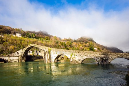 Téléchargez les photos : Le pont de Marie-Madeleine est une structure médiévale qui traverse la rivière Serchio. L'eau froide verte de la rivière reflète les anciennes arches asymétriques. Italie, province de Toscane - en image libre de droit