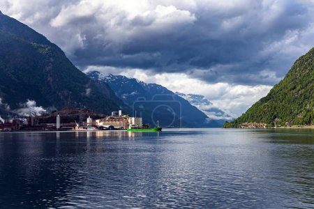 Photo for Small town of Odda. Magnificent Hardanger fjord between forested mountains. Magical late summer sunset illuminates the city and the water. Travel to Norway in summer. - Royalty Free Image