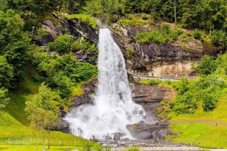 Téléchargez les photos : Huge bubbling waterfall Steinsdalsfossen. Exciting adventure in the north. Picturesque green country. Summer day in the mountains of Norway. - en image libre de droit