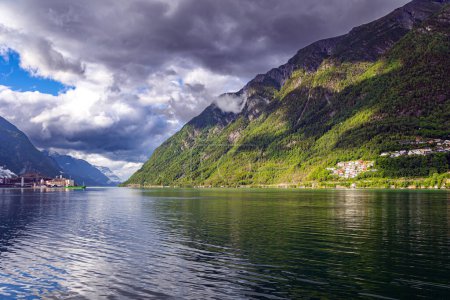 Photo for Magnificent Hardanger fjord between mountains. Small town of Odda. Travel to Norway in summer. Magical late summer sunset. Mountains and forests are reflected in the water. - Royalty Free Image