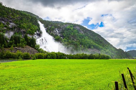 Photo for Norway. Huge powerful cascading waterfal Vidfossen. Scenic road in the mountains of Western Norway. White water foam envelops the foot of the waterfall.  Scandinavia. Summer, July. - Royalty Free Image