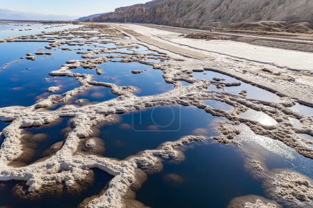 Téléchargez les photos : Mer Morte. Le lac salé sans drainage au Moyen-Orient, le lac le plus salé du monde. À la surface de l'eau, le sel évaporé forme des formes cristallines bizarres. Israël. La photo a été prise par un drone depuis une vue aérienne. - en image libre de droit