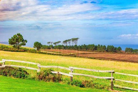 Photo for Green rural fields fenced with wooden fences. Picturesque road along the Atlantic Ocean. Romantic trip to Spain. Asturias. - Royalty Free Image