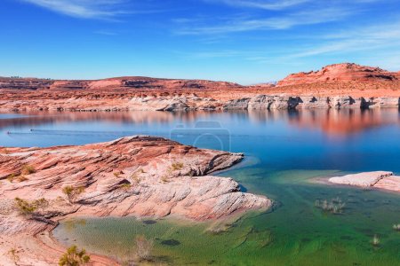Lake Powell. The smooth emerald water of the lake contrasts with sandstone shores. USA. The coast is cut by narrow canyons. The water reflects the surrounding shores