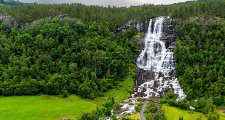 The colossal roaring waterfall Twindefossen. Exciting adventure in the north of Norway. Travel north. Picturesque green country in summer. The photo was taken from a drone. 