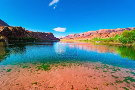 Photo for The multicolored canyon of red, orange, and yellow Navajo sandstones. The water of the Colorado River reflects the steep rocks. The historic Lees Ferry on the Colorado River. - Royalty Free Image
