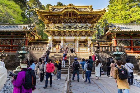 Photo for NIKKO, JAPAN, APRIL 22, 2023: Visitors to the temple and shrine of Nikko Tosho-gu. Japan. Ornate temple with gilded roof. Building complex built in 1617. Sunset. - Royalty Free Image