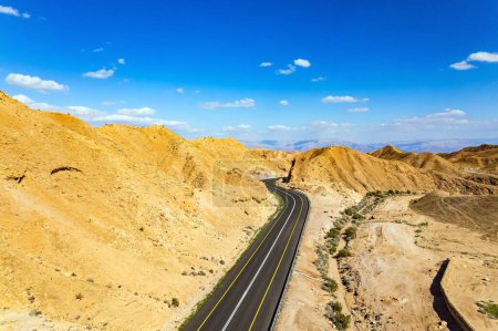 Israel. Desierto a orillas del Mar Muerto. La autopista del asfalto serpentea entre las colinas. El lodo del Mar Muerto tiene propiedades curativas. Vista de pájaro.