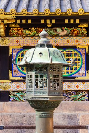 Magnificent stone lantern. Ornate temple with gilded roof. Japan.The temple and shrine of Nikko Tosho-gu is dedicated to the shogun Tokugawa Ieyasu. Building complex built in 1617. 